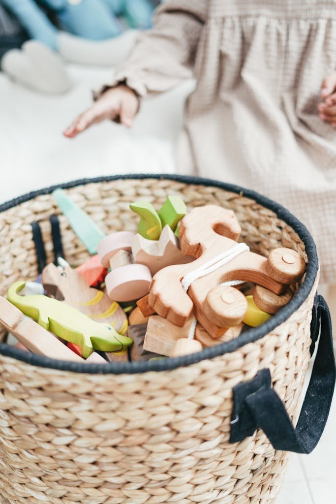 A child's hand reaching for colorful wooden toys in a woven basket, capturing playtime joy.