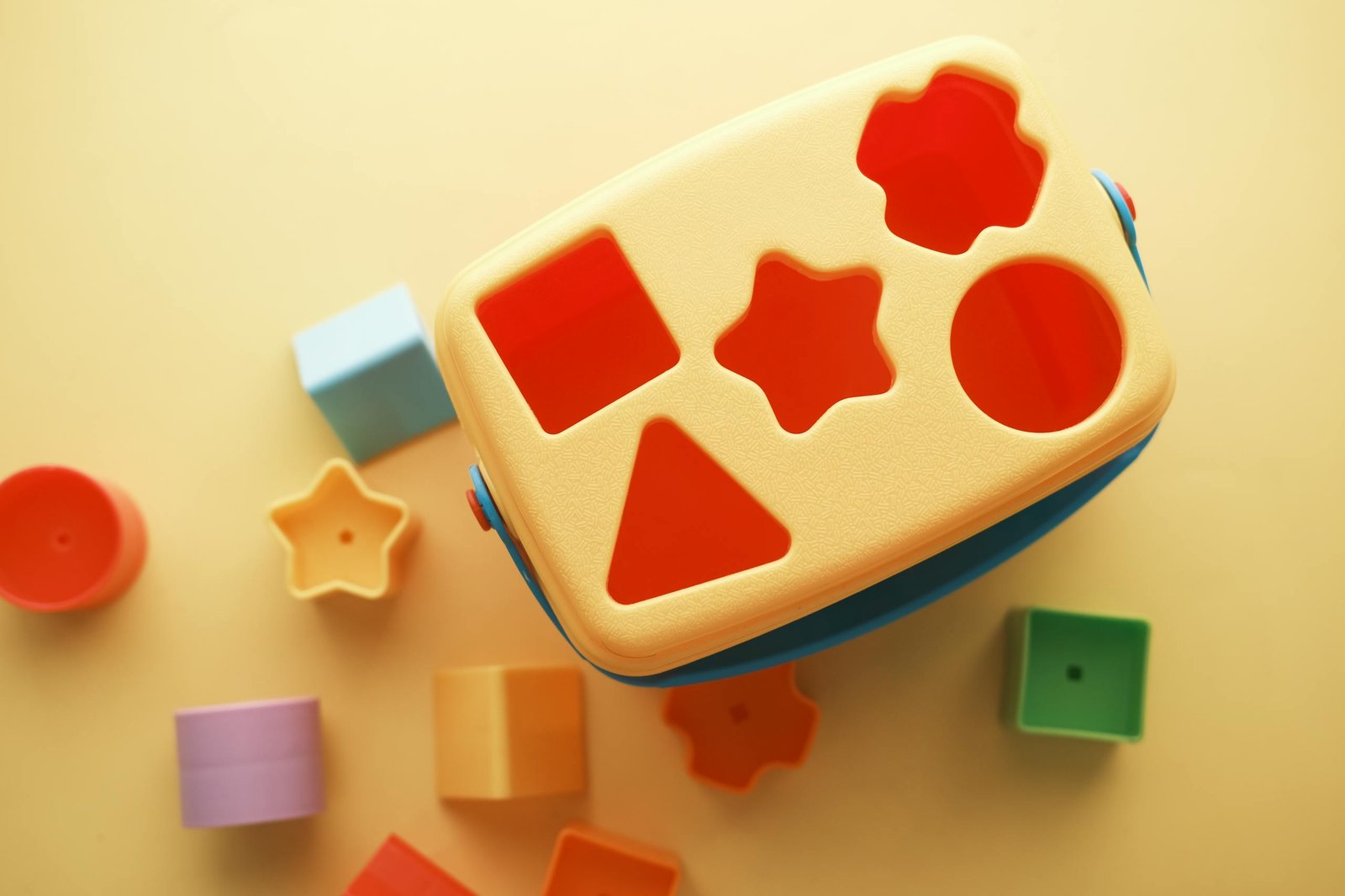 A vibrant shape sorter toy with various blocks on a yellow background, perfect for early childhood education.