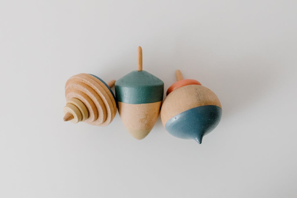 Close-up of three colorful wooden spinning tops on a white surface.