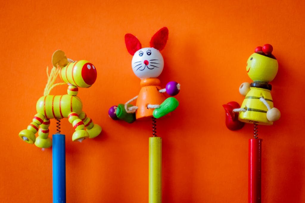Close-up of three colorful wooden toys on a vibrant orange background, perfect for children's themes.