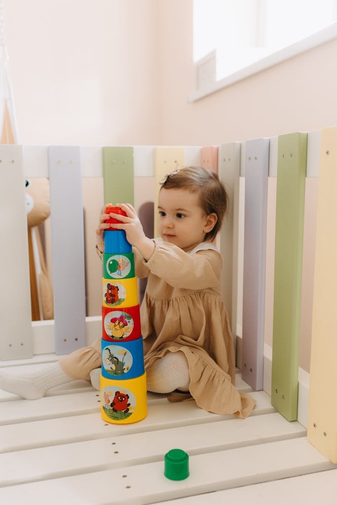 Cute toddler playing with colorful stacking cups in a cozy indoor setting.