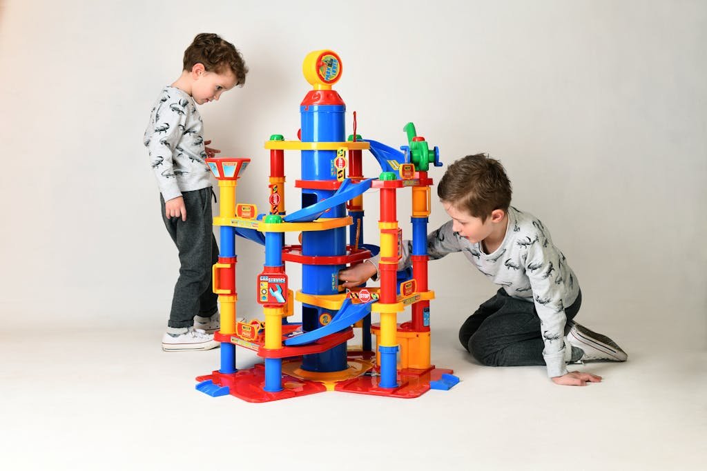 Two boys enjoying playtime with a colorful construction toy in a well-lit studio setting.