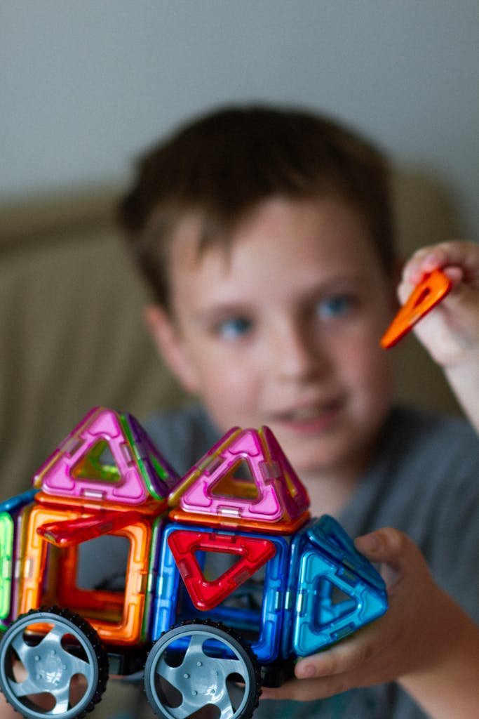 Young boy building with vibrant magnetic toy blocks, focusing on creativity and play indoors.