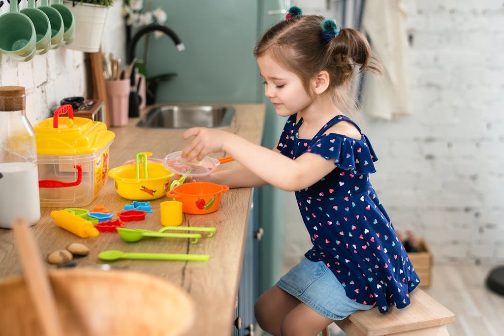 Young girl engaged in imaginative play with kitchen toys on a countertop.